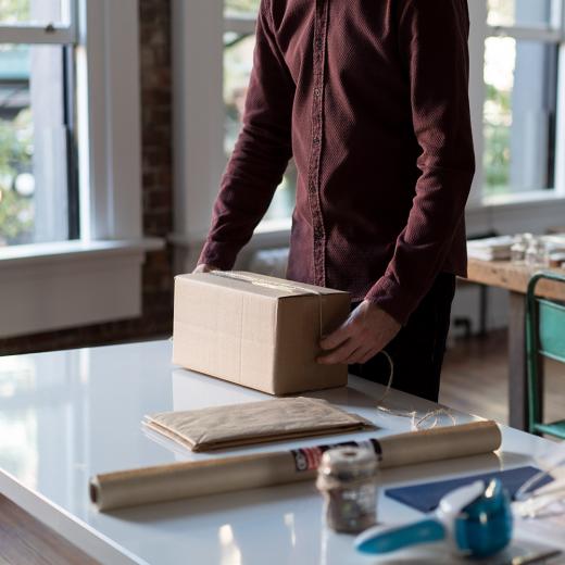 Signet's Packaging Supplies Being Used By A Small Business Owner To Pack Goods For Their Home Online Business