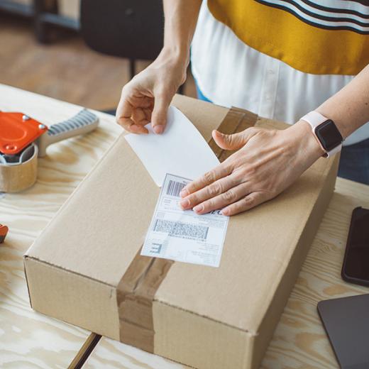 Person applying shipping label to carton