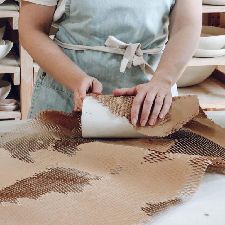 An Individual Using Eco Friendly Sustainable Packaging Wrapping Paper To Pack A Product