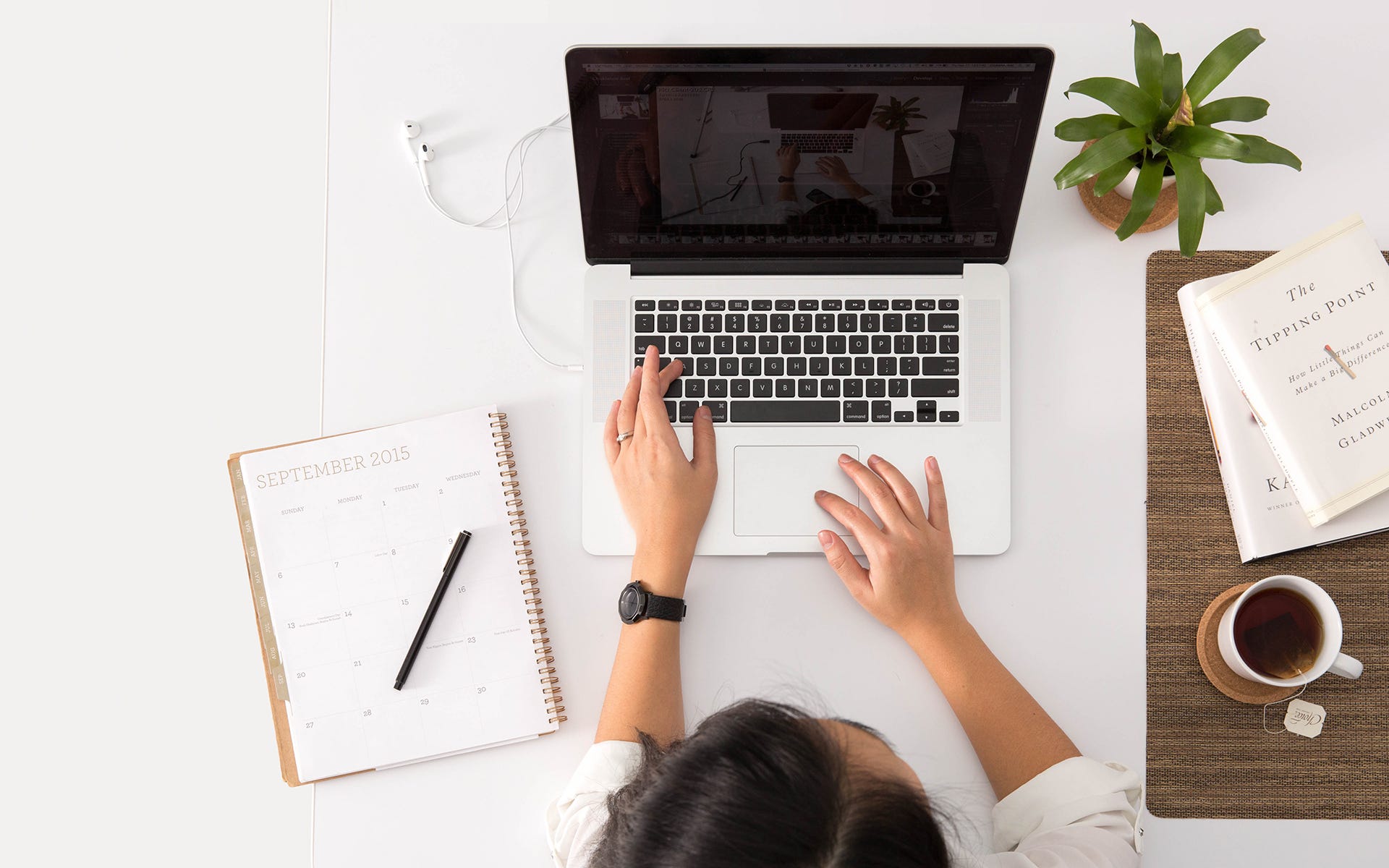 An Individual Using A Laptop To Research For Their Home Online Business And Using A Planner To Note Down Points