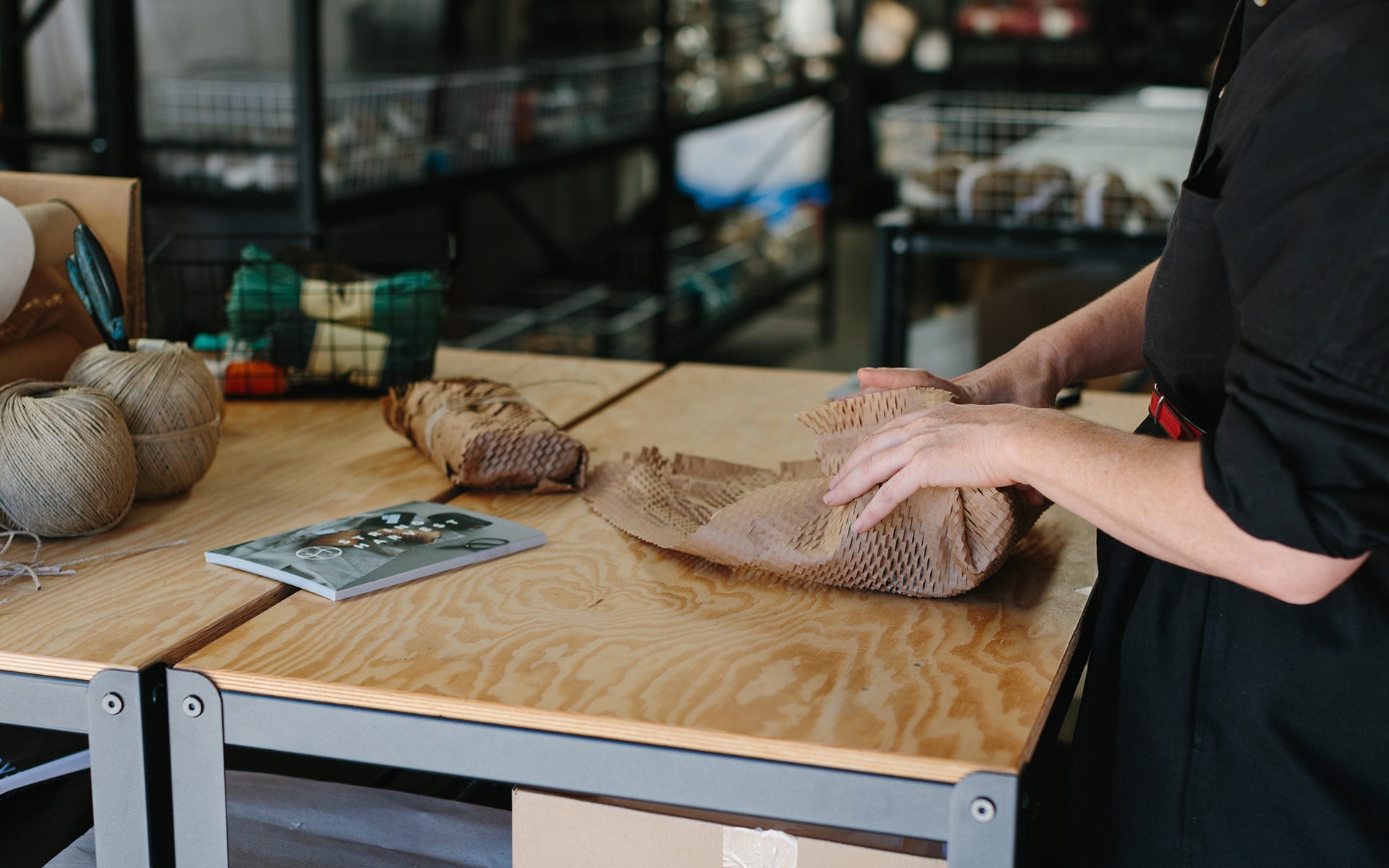 An Individual Using Signet's Eco Friendly Plastic Free Wrapping Paper To Package Goods From Their Home Online Business