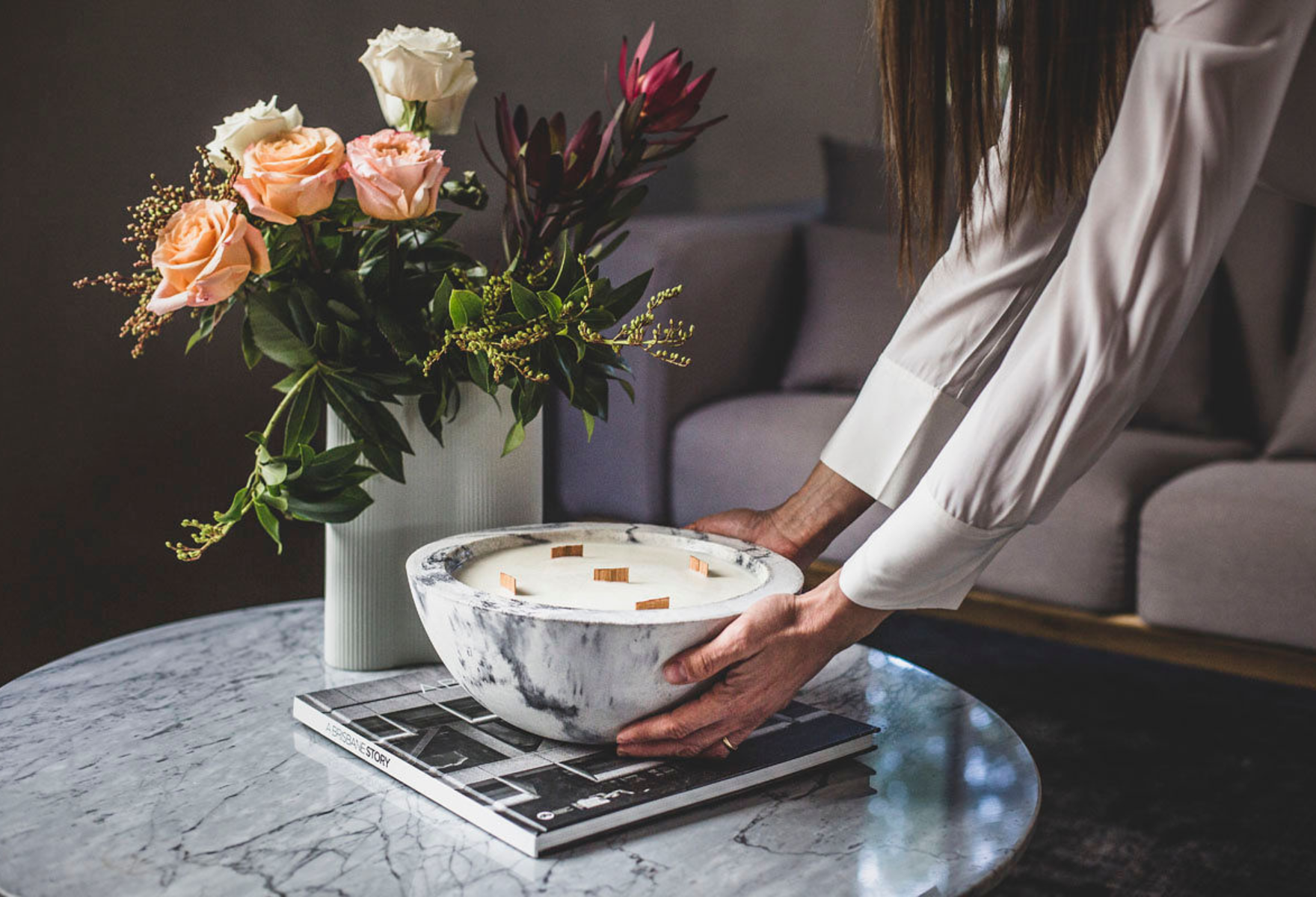 Lumen + Luxe candle on marble table with flowers
