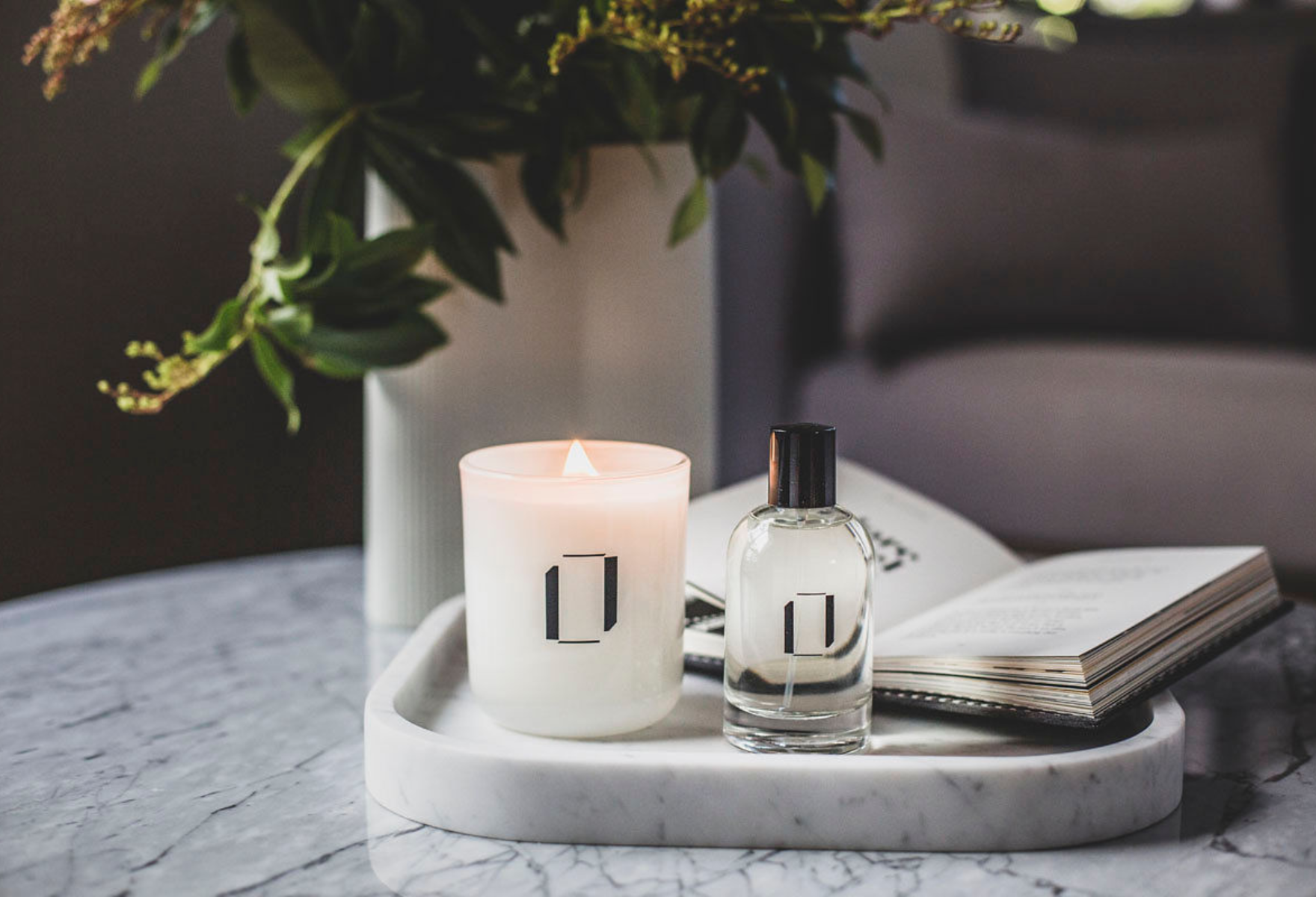 Lumen + Luxe candle and room spray on marble table with flowers
