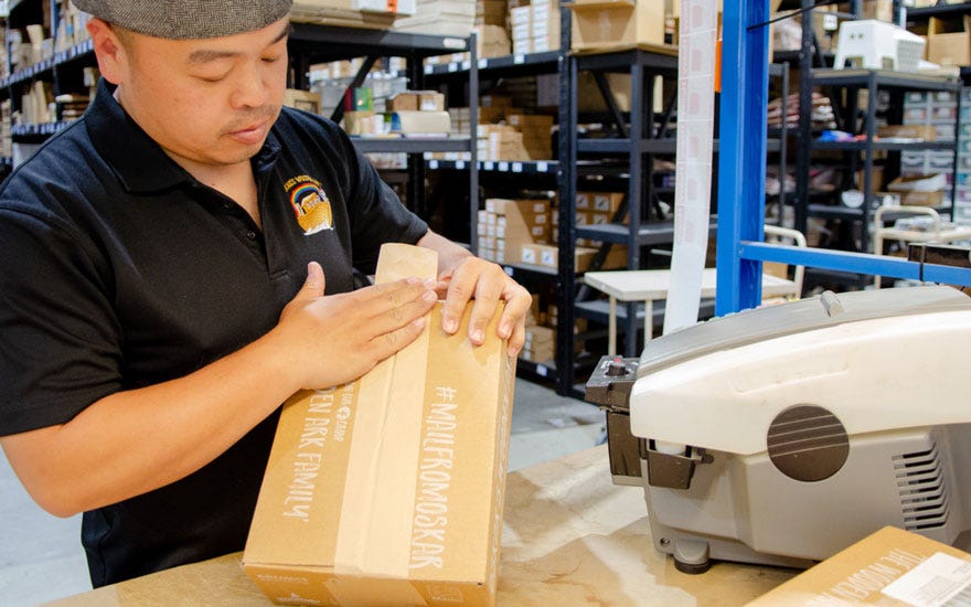 Oskar's Wooden Ark employee sealing carton with WAT