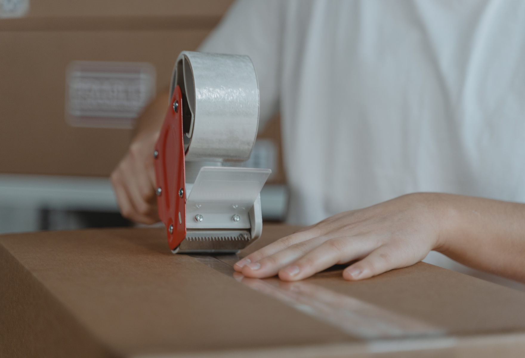 Person sealing carton with hand packaging tape with packaging tape dispenser Person sealing carton with hand packaging tape with packaging tape dispenser